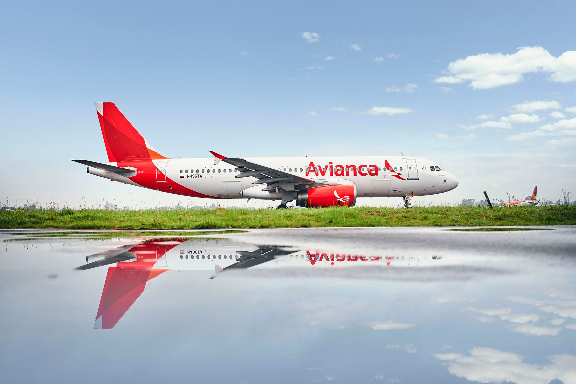 Avianca plane on an airport runway with it's reflection visible in a puddle