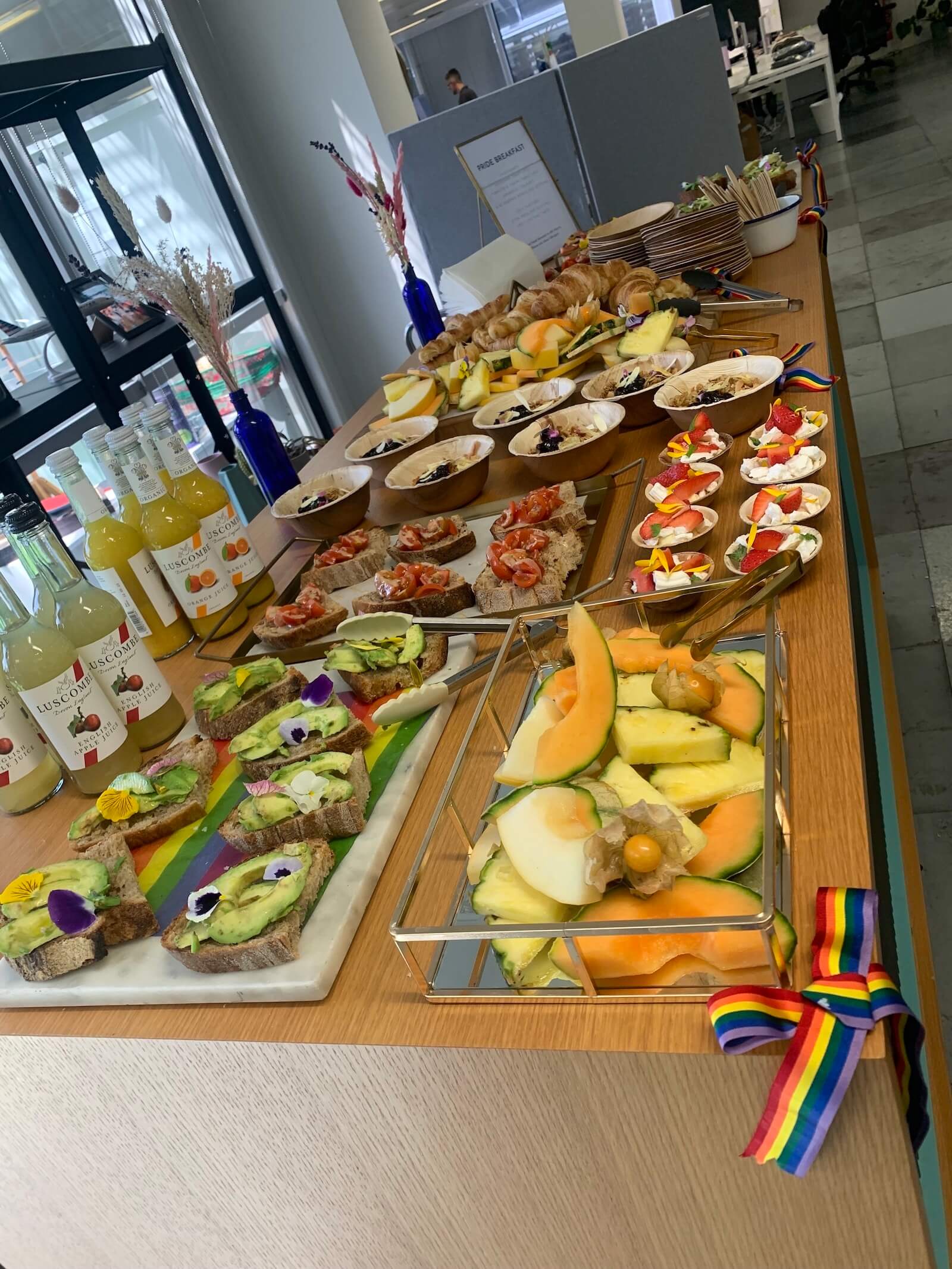 Assorted food and drink laid out on a table with a rainbow ribbon in the foreground.